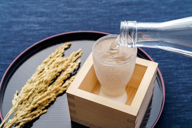 グラスに注がれる日本酒と稲穂